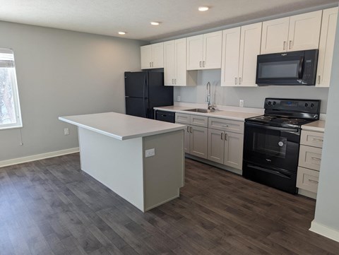 a kitchen with white cabinets and black appliances